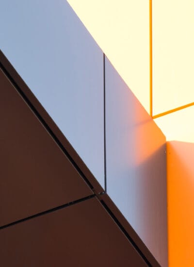 Geometric color elements of the building facade with planes, lines, corners with highlights and reflections for an abstract background and texture of gray, orange colors. Place for text